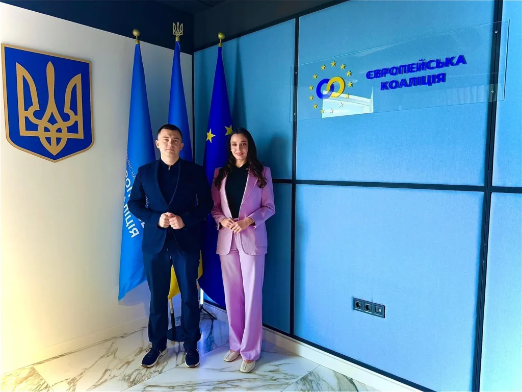 Group photo after the signing of the Memorandum, in front of the Ukrainian coat of arms and the “European Coalition” backdrop