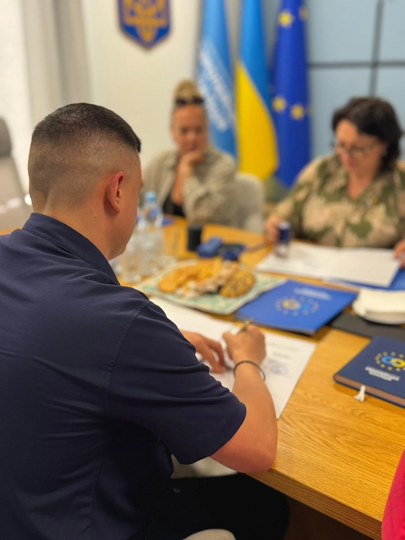 A participant signing documents at the negotiating table