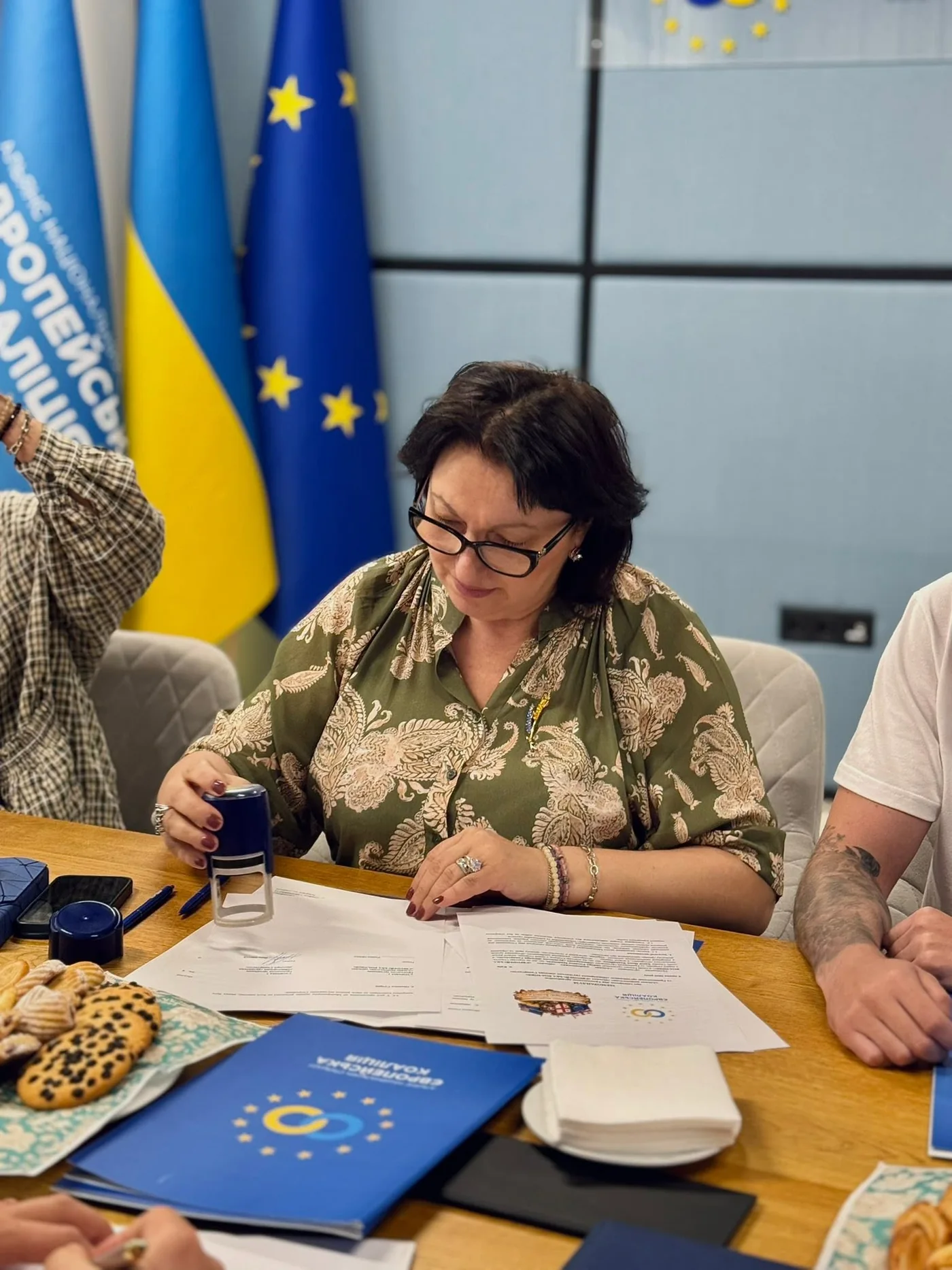 A representative of «Сакартвело» signing documents in front of the Ukrainian and EU flags